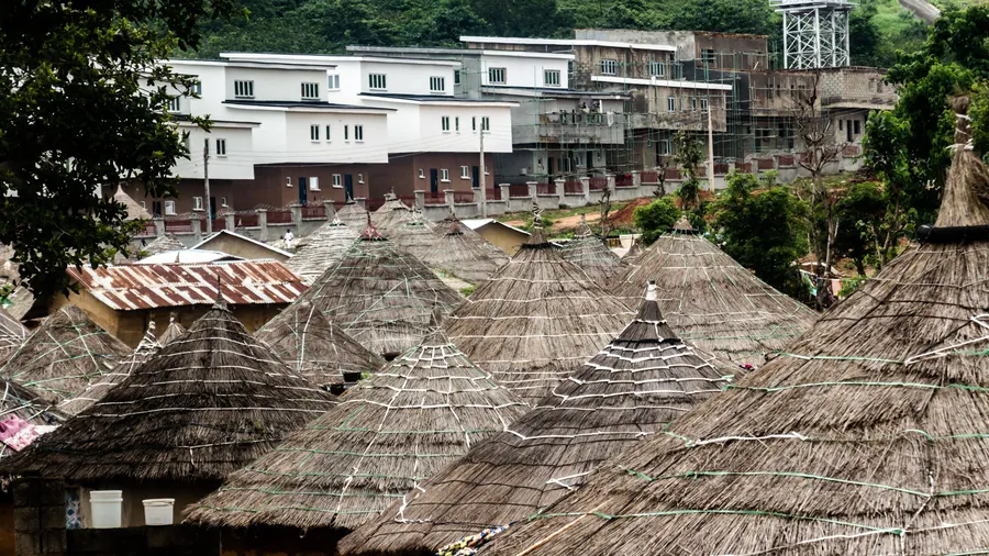 Contraste entre chozas de techo de paja y edificios modernos en Abuya, Nigeria
