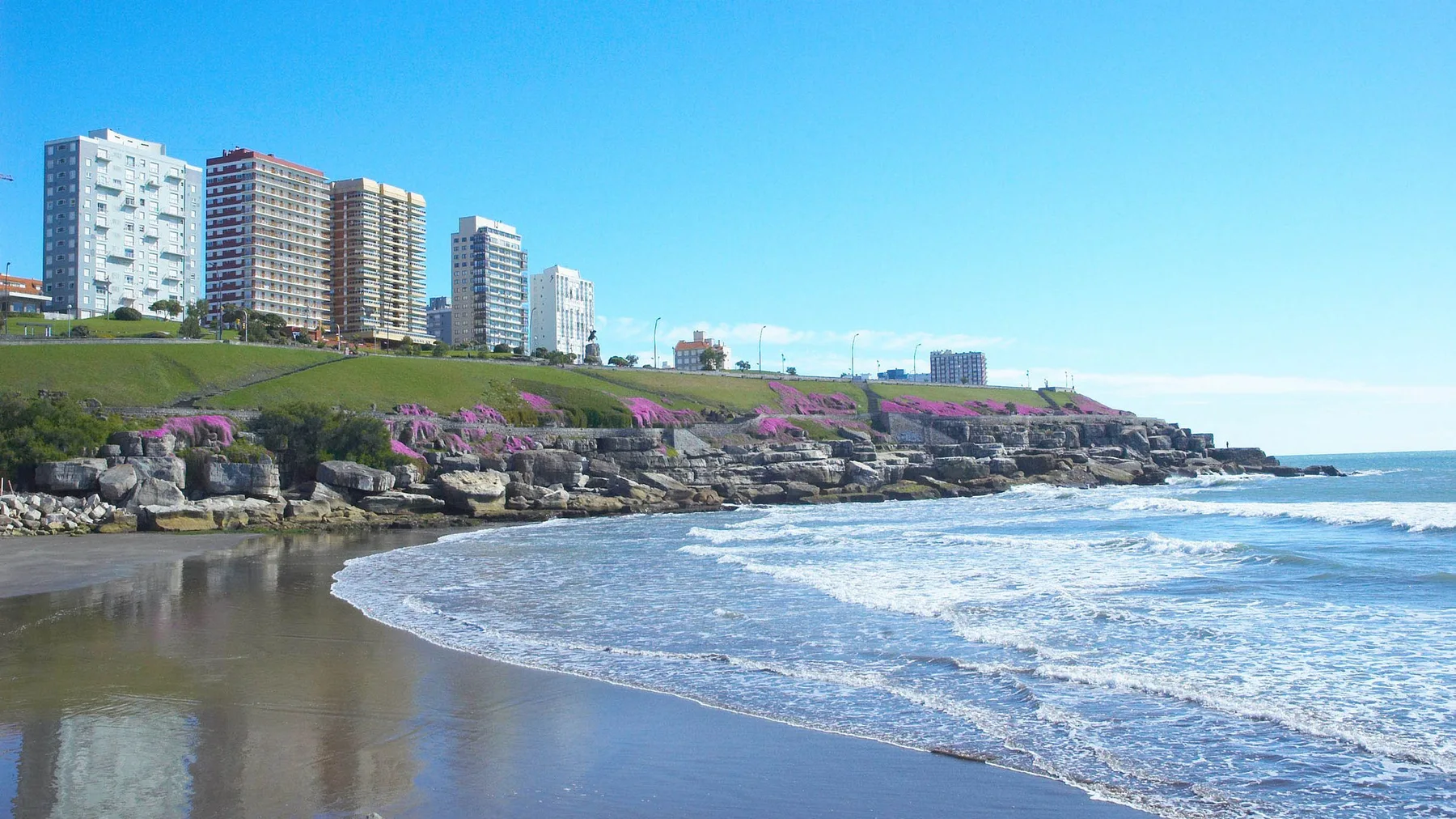 Vista de la costa y el skyline de Mar del Plata con olas rompiendo bajo un cielo despejado