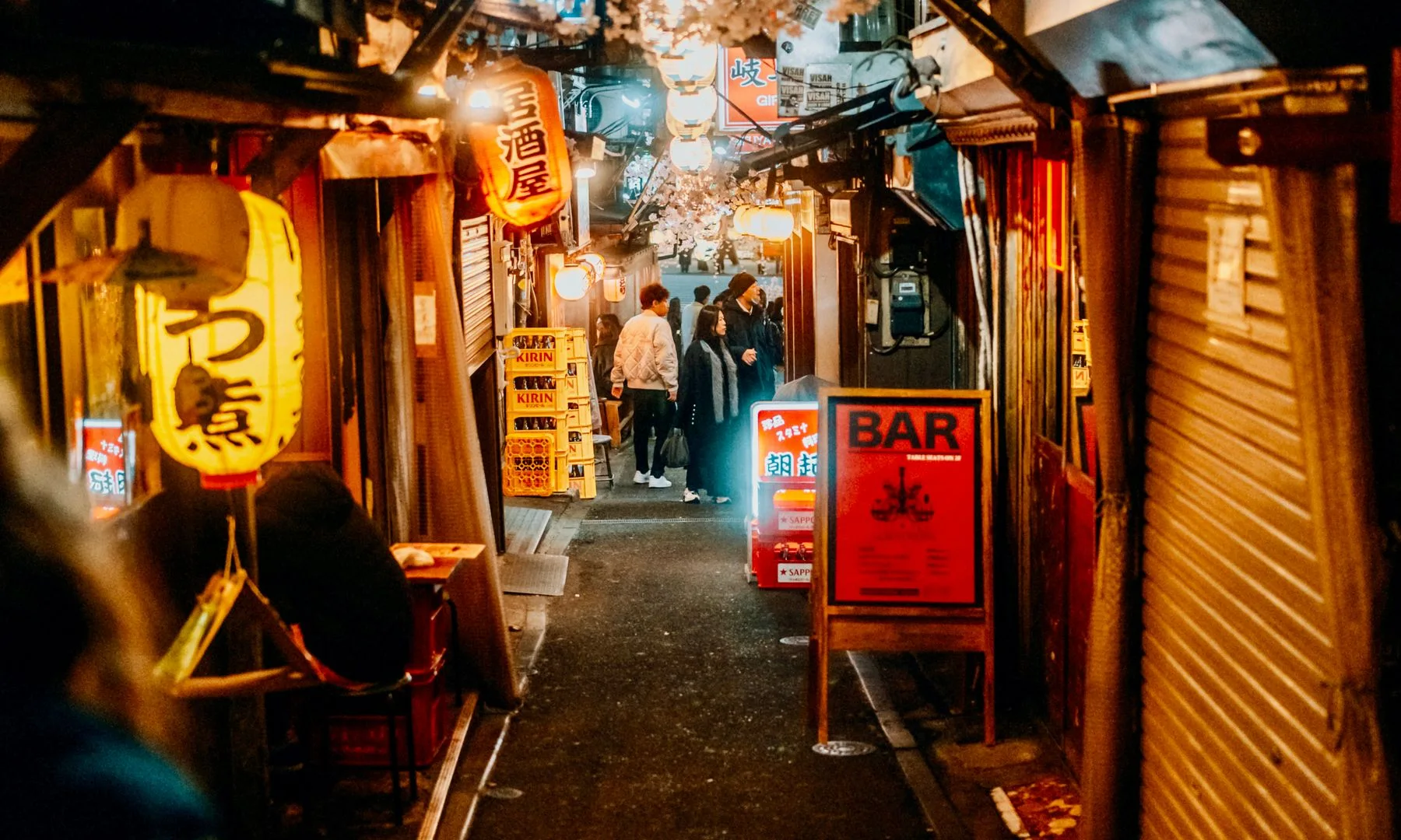 Callejón de Tokio de noche con letreros de bares y luces de neón, en un ambiente urbano animado