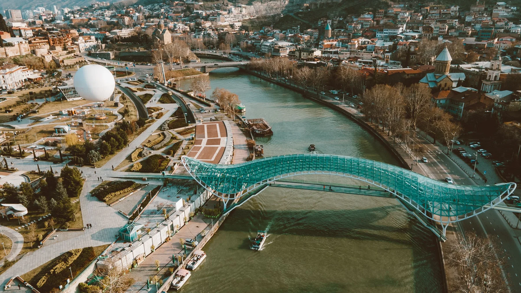 Vista aérea del Puente de la Paz sobre el río Kura en Tiflis, con el paisaje urbano de la ciudad