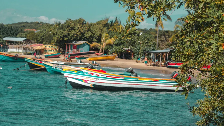 Barcos coloridos amarrados junto a una playa de Jamaica bajo un cielo despejado