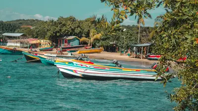 Barcos coloridos amarrados junto a una playa de Jamaica bajo un cielo despejado