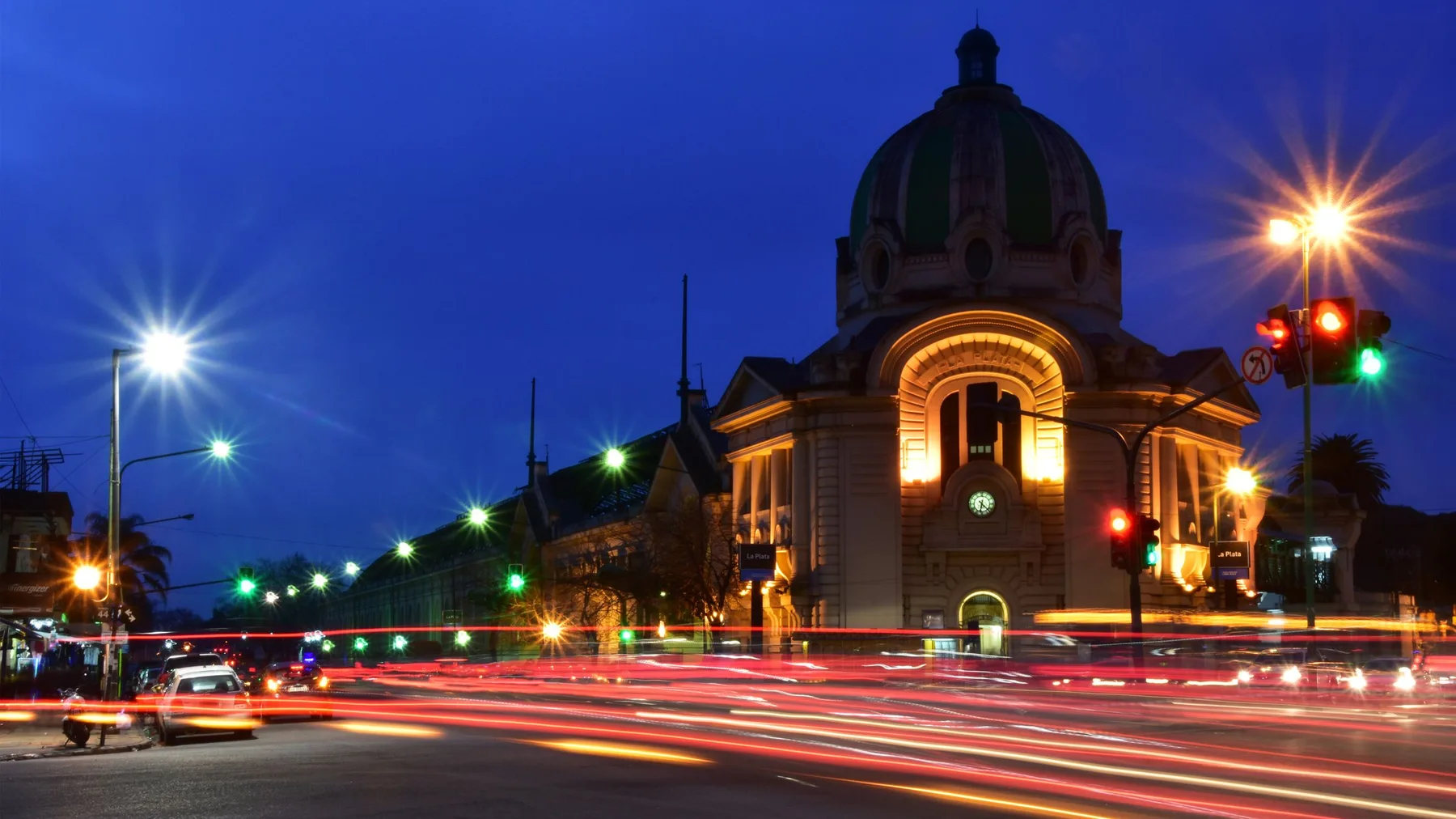 Vista nocturna de un edificio histórico de La Plata con estelas de luz y colores vibrantes