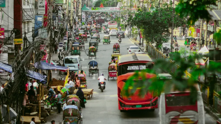 Calle transitada de Daca con tráfico local intenso y ambiente urbano