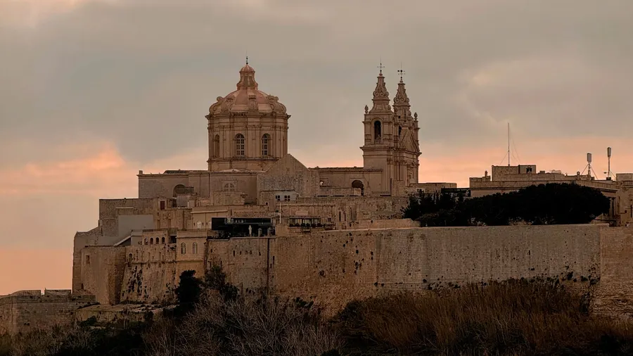 Vista de Mdina al atardecer, con su arquitectura histórica y un cielo dramático sobre Malta