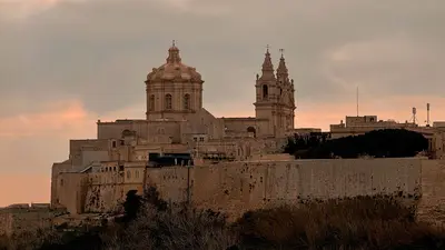 Vista de Mdina al atardecer, con su arquitectura histórica y un cielo dramático sobre Malta