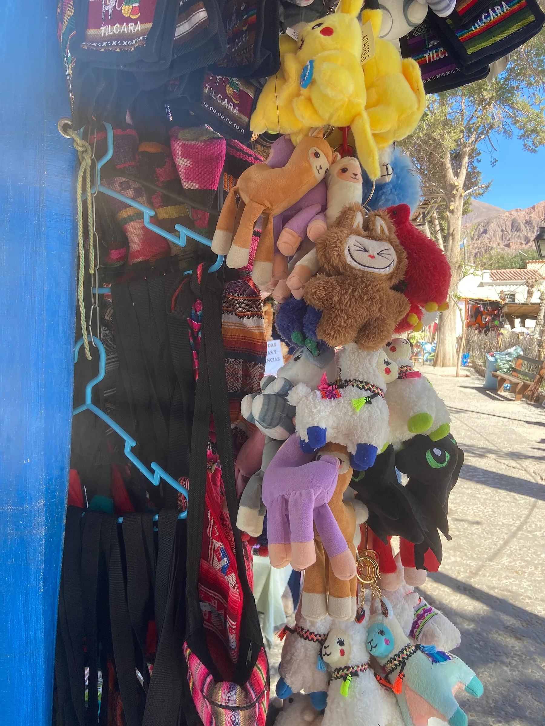 Puesto de feria en Tilcara con artesanías tradicionales andinas y pequeños souvenirs, entre ellos muñecos Labubu y referencias a personajes digitales actuales