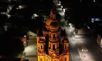Vista aérea nocturna de la Catedral de Aguascalientes iluminada entre la ciudad