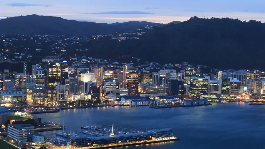 Vista aérea nocturna del perfil urbano de Wellington con las luces reflejadas en el paseo marítimo