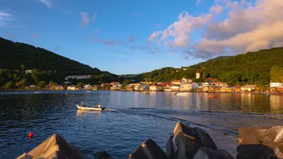 Atardecer sobre la bahía de Deshaies, en Guadalupe, con un pequeño bote en primer plano