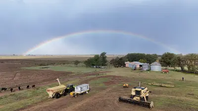 Arcoíris sobre un campo pampeano con maquinaria agrícola y galpones
