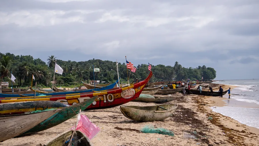 Botes de pesca de madera de colores alineados en la playa de arena de Robertsport, Liberia