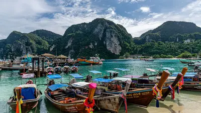 Botes de madera de colores anclados en una bahía rodeada de colinas verdes en Phuket, Tailandia