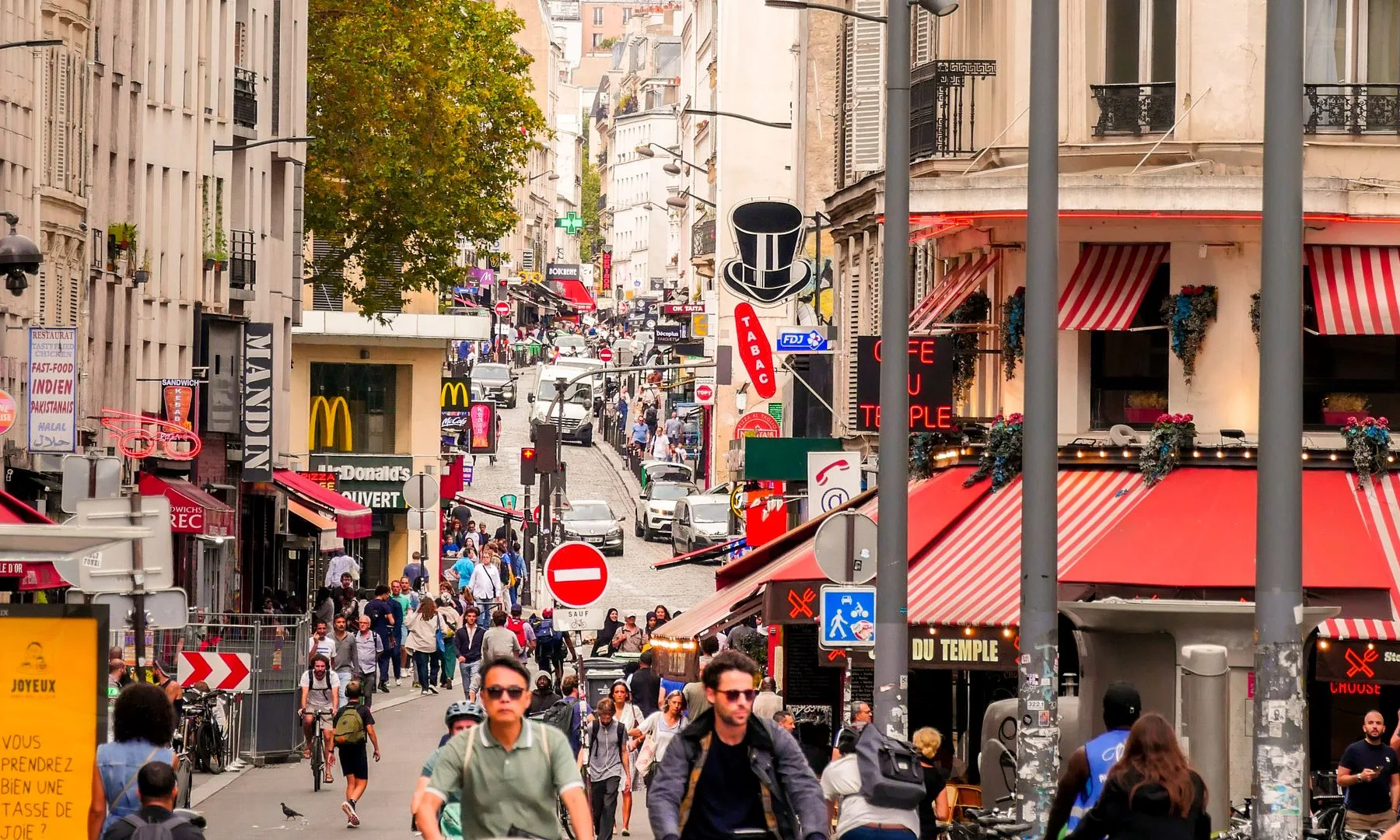 Calle concurrida de París con ciclistas y peatones, que muestra la vida urbana de Île-de-France