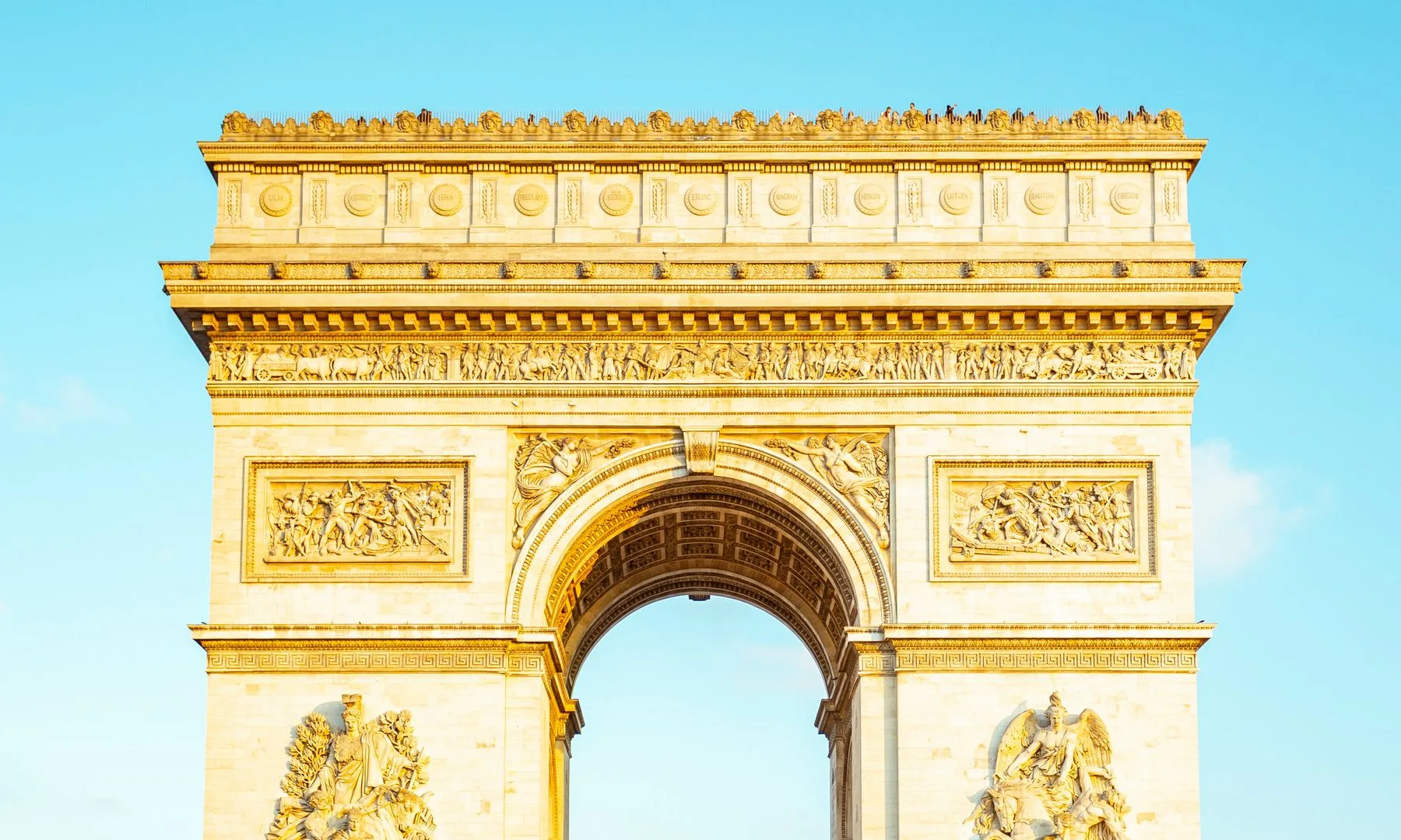 Vista del icónico Arco del Triunfo en París bajo un cielo azul claro.
