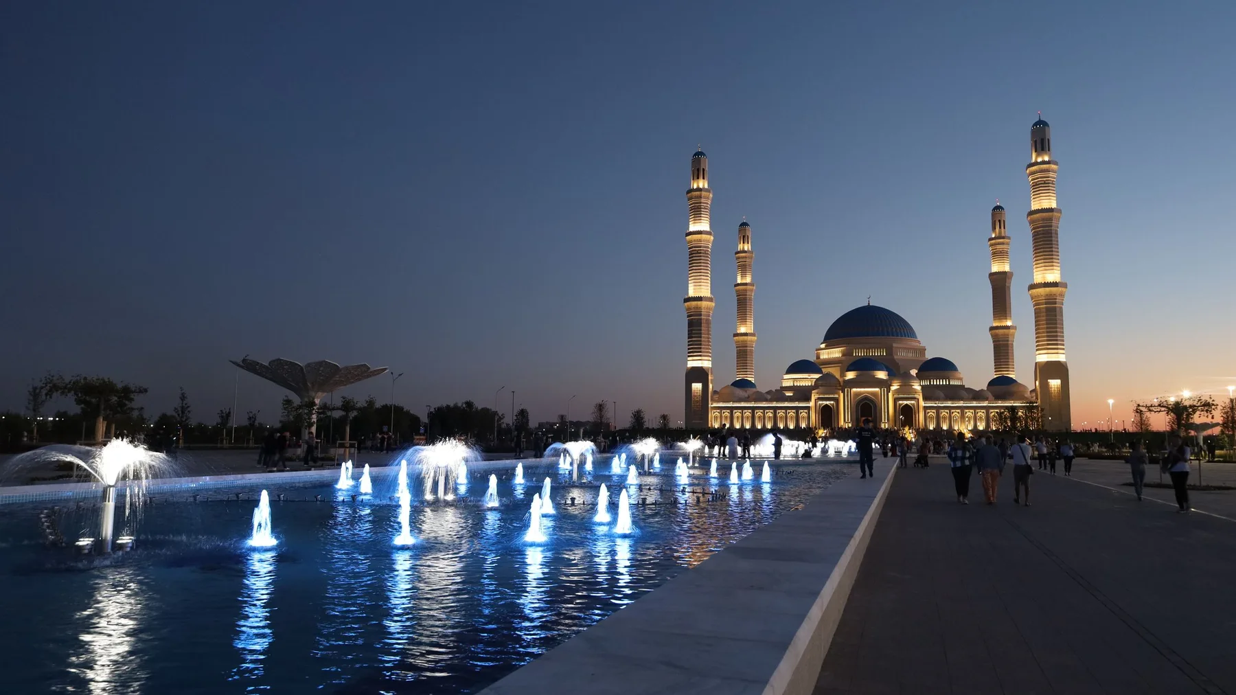 Mezquita Hazrat Sultan iluminada al atardecer, con fuentes reflejadas, en Astaná, Kazajistán