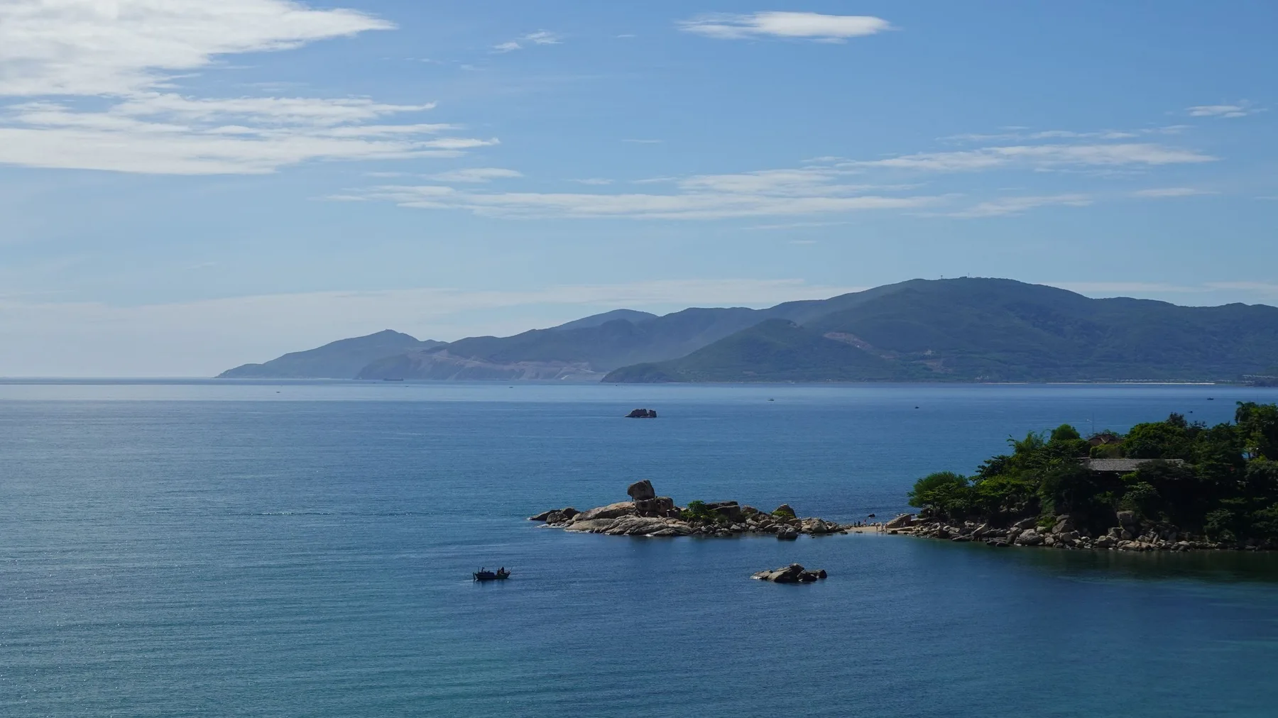 Vista panorámica de la costa de la Provincia de Trang, con mar azul tranquilo y montañas al fondo