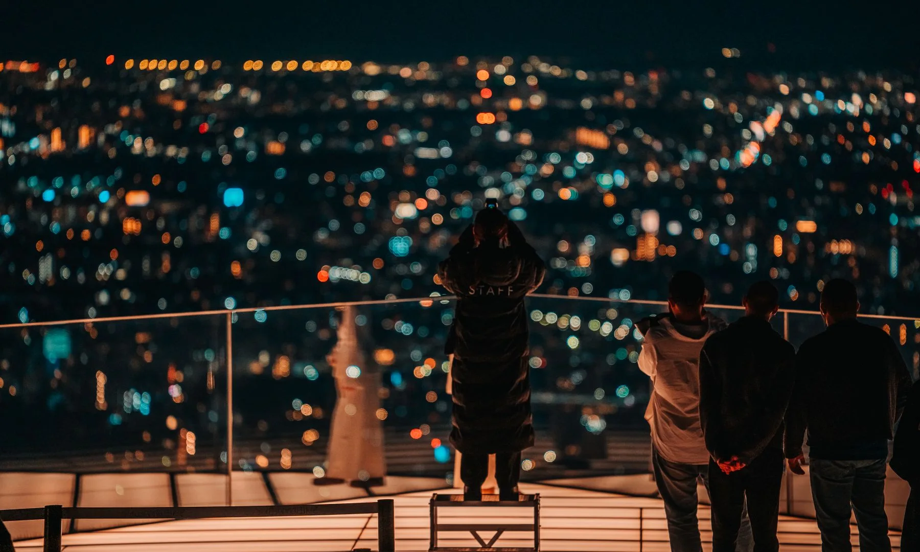 Grupo observando el paisaje nocturno de Tokio desde una azotea en Shibuya