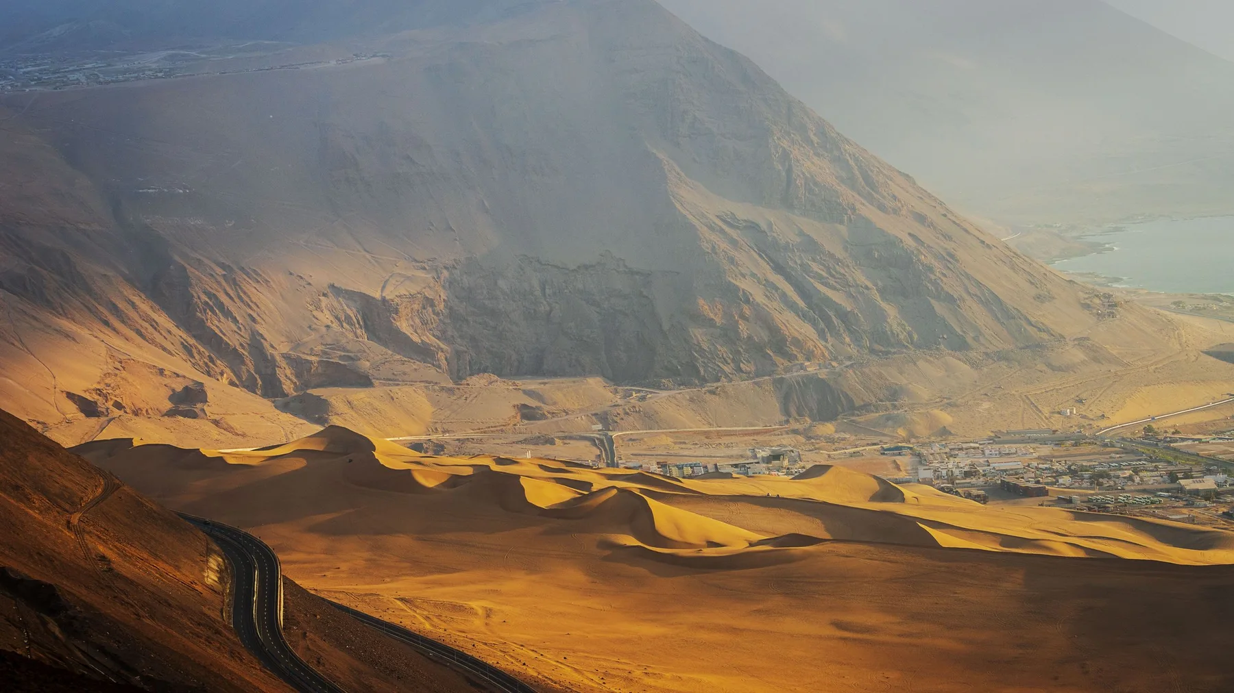 Vista aérea del paisaje árido de Iquique, Tarapacá, con caminos sinuosos y dunas de arena