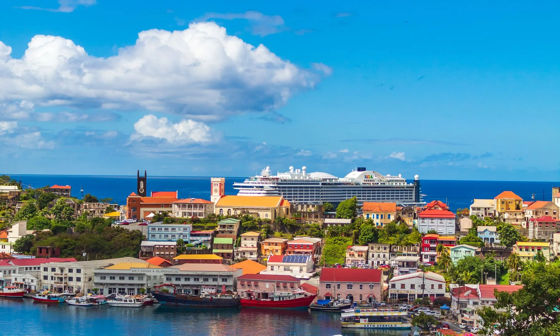 Vibrant harbor view in St. George's, Grenada with colorful buildings and boats under a bright blue sky.