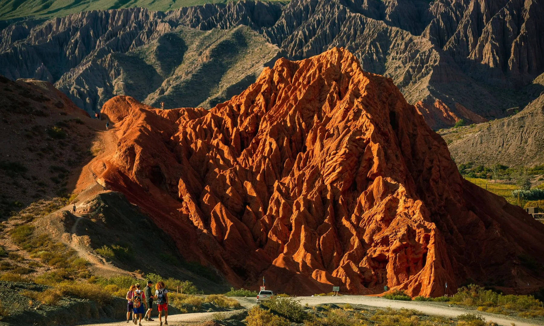 Caminantes recorren cerros rojizos en el Paseo de los Colorados de Purmamarca, bajo un cielo despejado