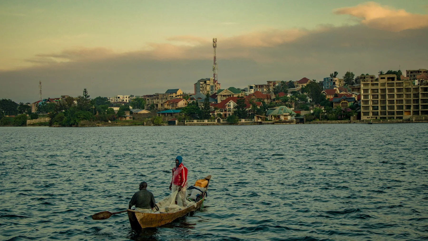 Dos pescadores en una barca de madera tradicional en el lago Kivu, cerca de Goma, durante el atardecer