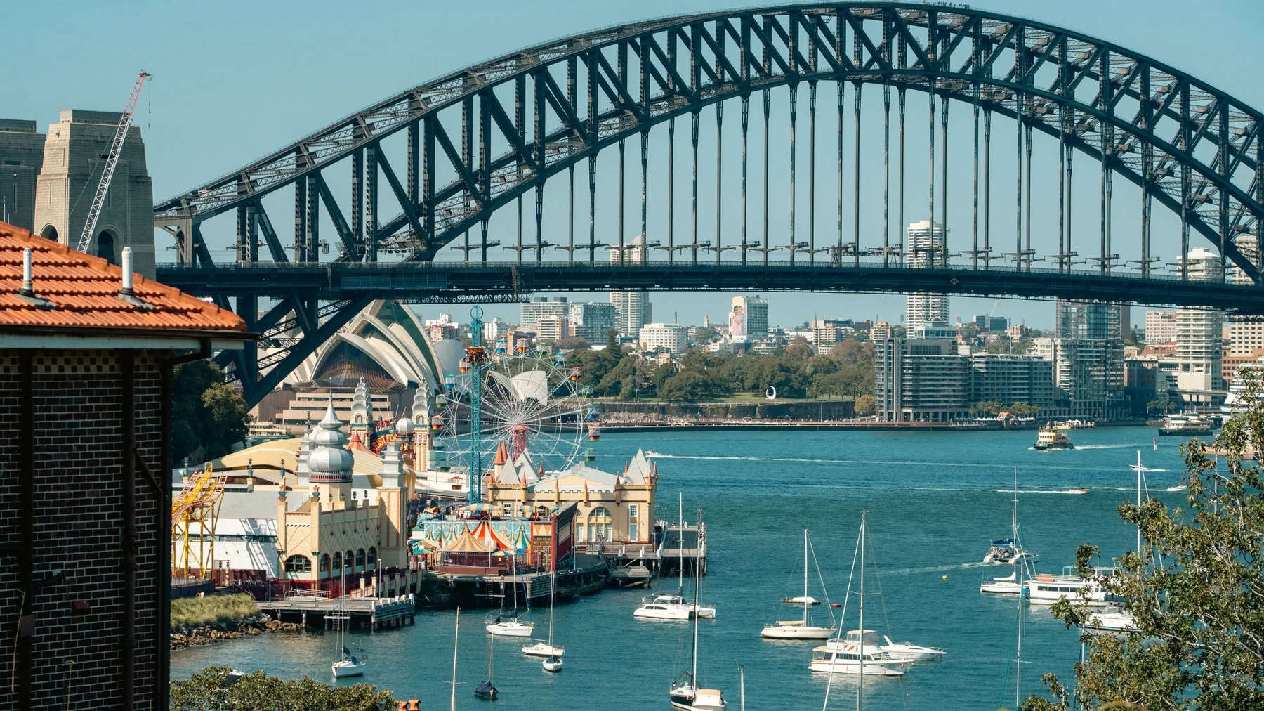 Vista del Sydney Harbour Bridge con Luna Park y veleros en la bahía de Sídney