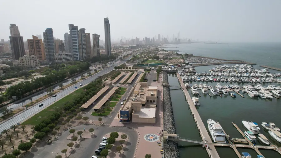 Vista aérea del horizonte moderno de Ciudad de Kuwait y su puerto concurrido con yates