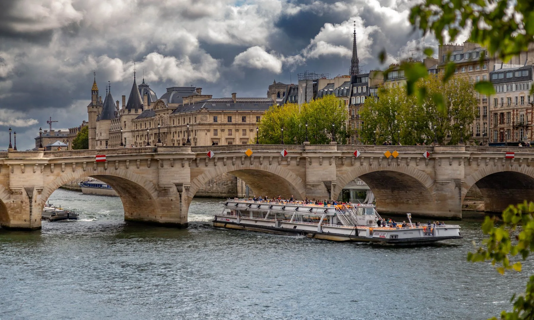 Scenic view of the historic Pont Neuf and a cruise boat on the Seine in Paris.
