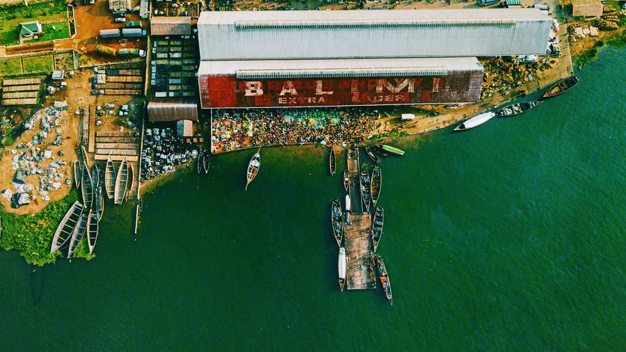 Aerial shot of a bustling port along Lake Victoria in Mwanza, Tanzania, with boats and warehouses.