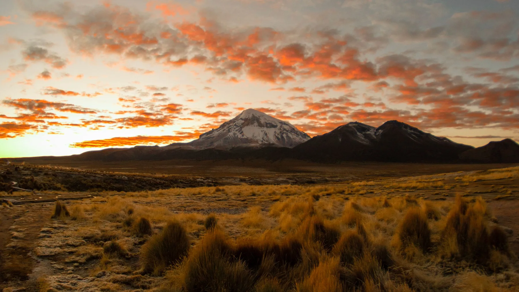 Atardecer sobre montañas y llanuras de pastizales en el altiplano de Oruro, Bolivia