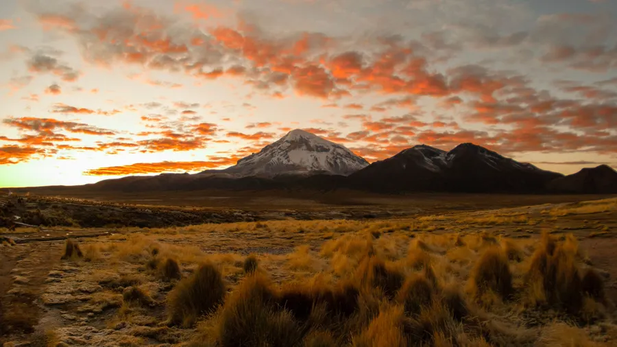 Atardecer sobre montañas y llanuras de pastizales en el altiplano de Oruro, Bolivia