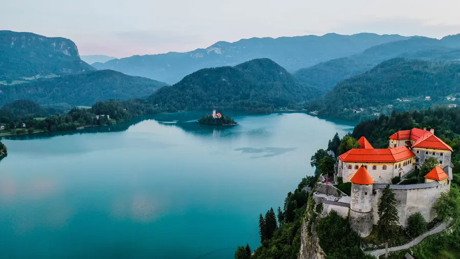 Vista aérea del castillo de Bled sobre el lago Bled, en Eslovenia, con montañas alrededor