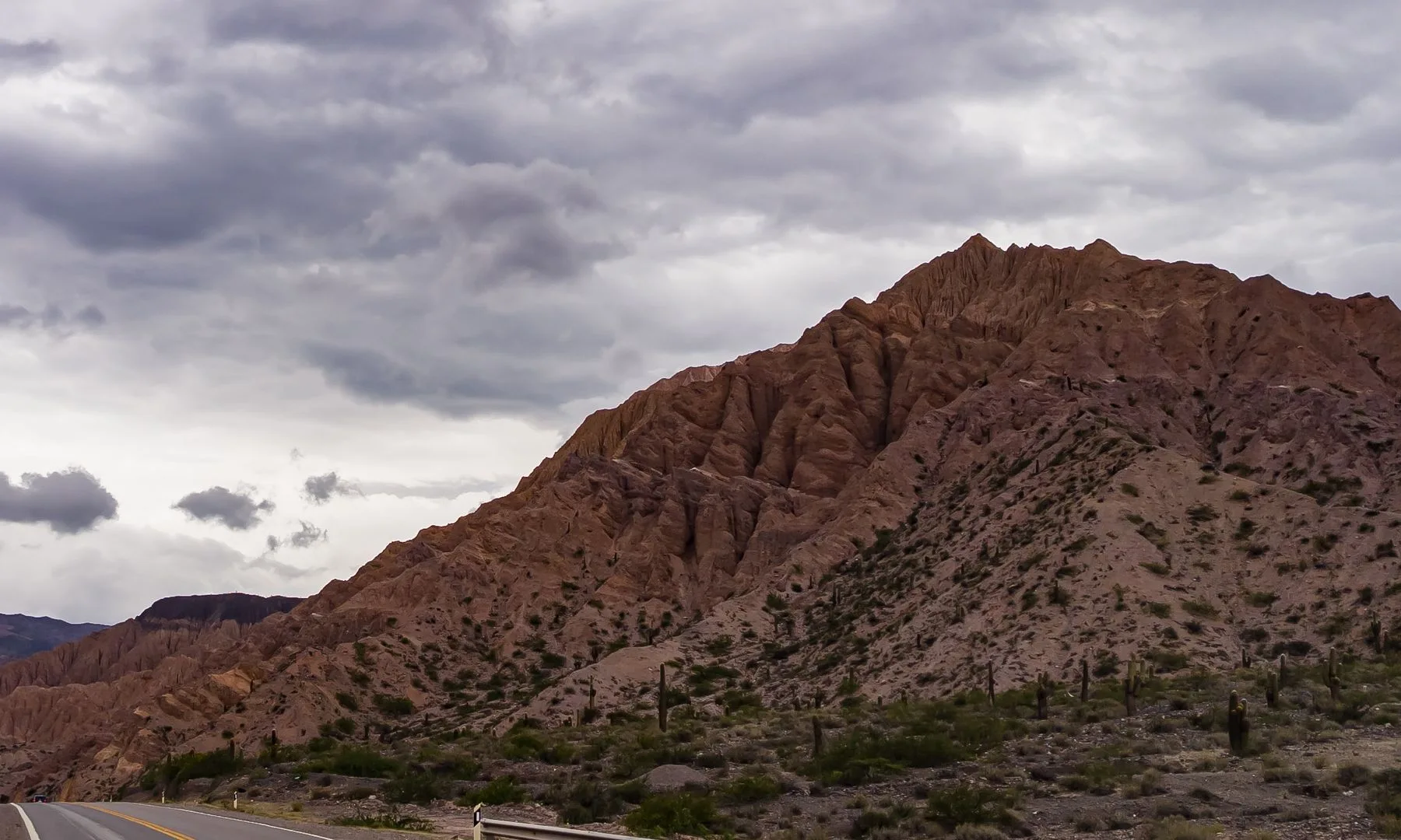 Dramatic sky over the Quebrada de Humahuaca in Jujuy, Argentina, featuring a winding road and rocky mountains.