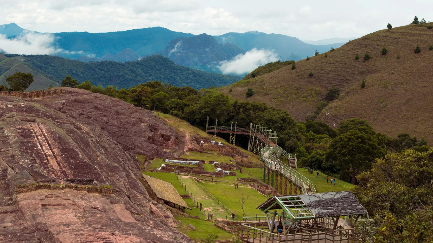 A scenic view of the Samaipata archaeological site amidst lush hills and clouds.