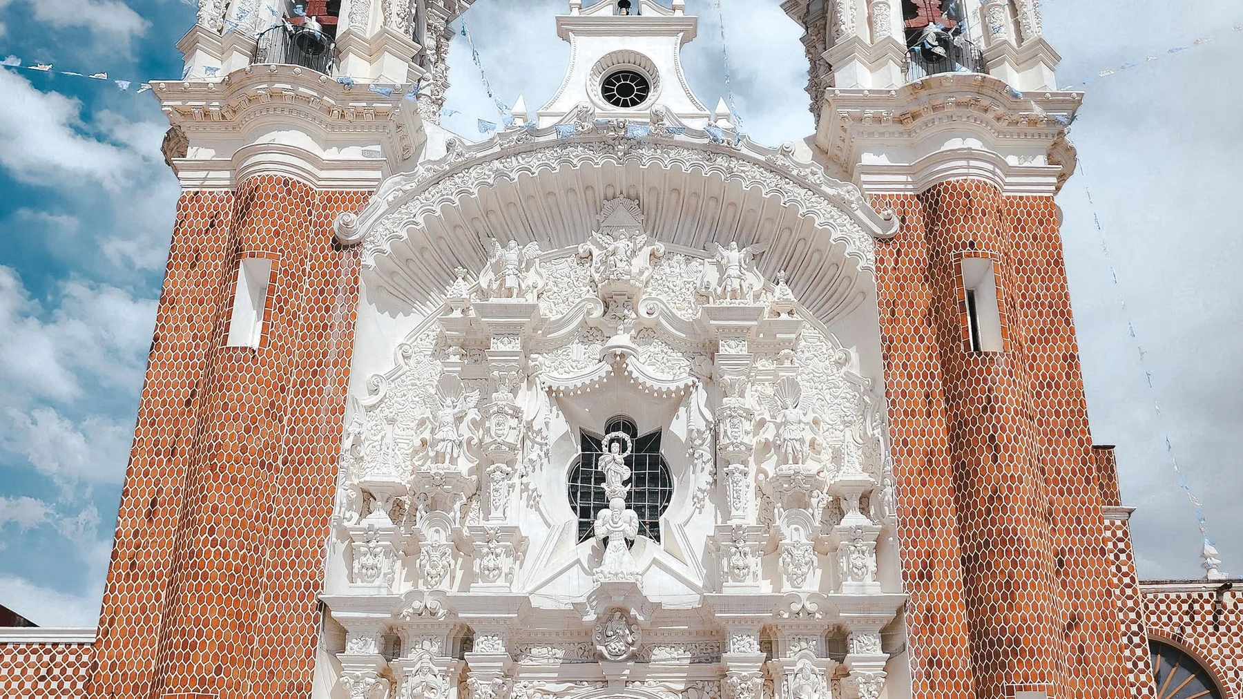 Iglesia barroca de fachada intrincada bajo un cielo luminoso en Tlaxcala, México