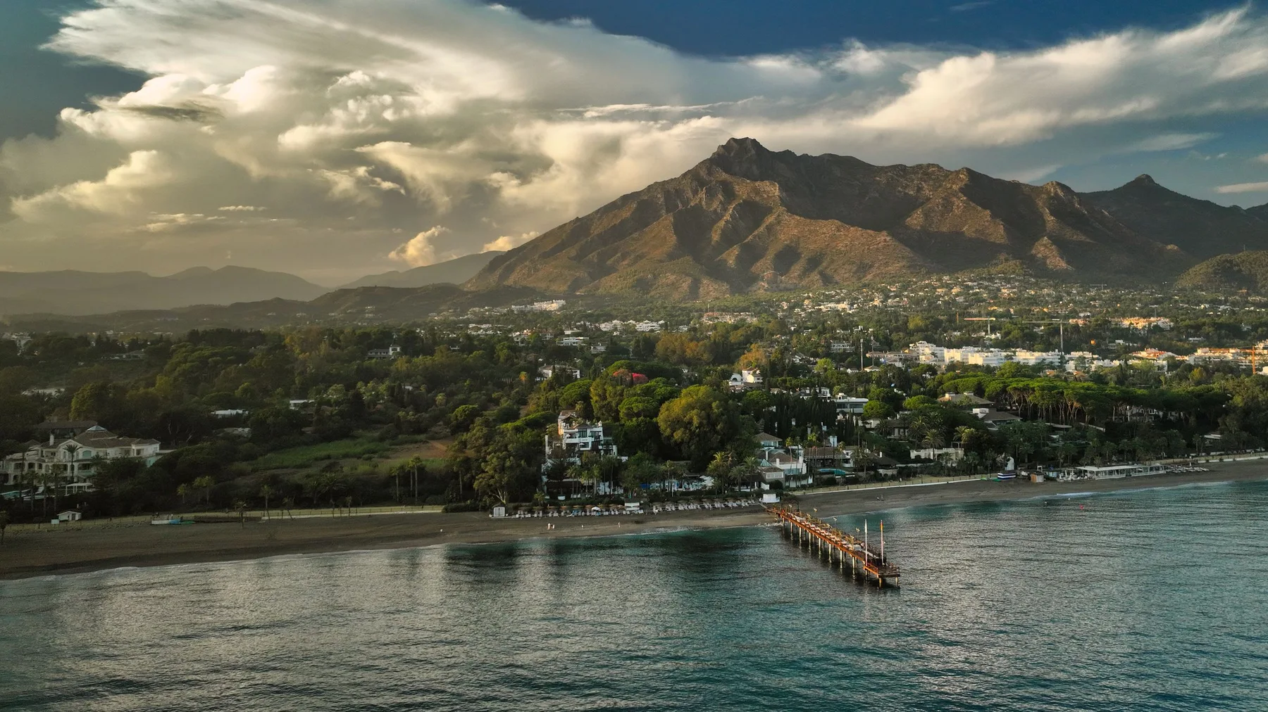 Vista aérea de la costa de Marbella con vegetación y montañas al fondo