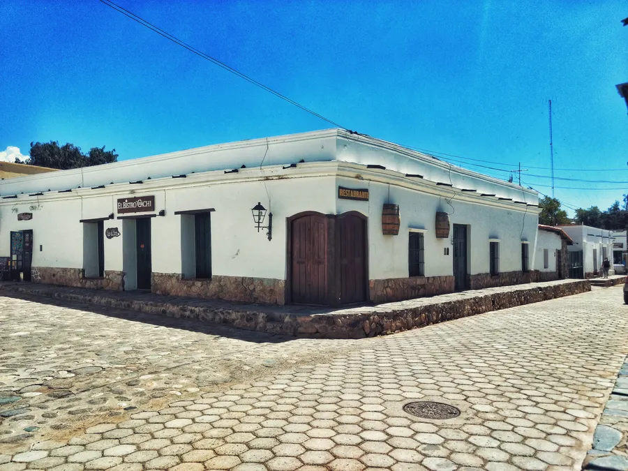 Calle adoquinada del casco histórico de Cachi, con casas bajas y montañas al fondo