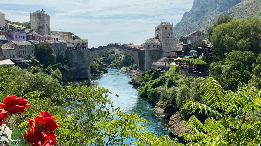 Vista del Puente Viejo y el río en Mostar, con flores vibrantes en primer plano