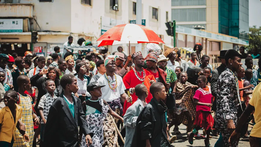 Desfile callejero en Accra con personas vestidas con atuendos tradicionales