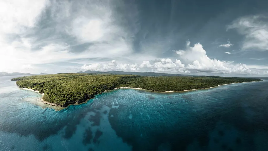 Vista aérea de la costa verde de Vanuatu, rodeada de aguas cristalinas