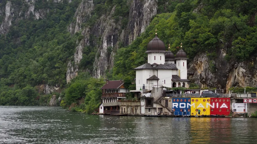 Iglesia ortodoxa junto al Danubio con montañas al fondo, en Rumanía