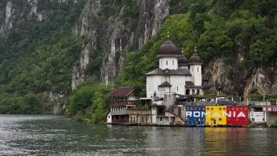Iglesia ortodoxa junto al Danubio con montañas al fondo, en Rumanía