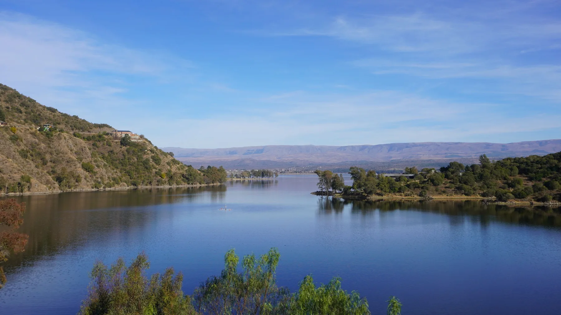 Vista de un lago rodeado de sierras boscosas en Córdoba, Argentina