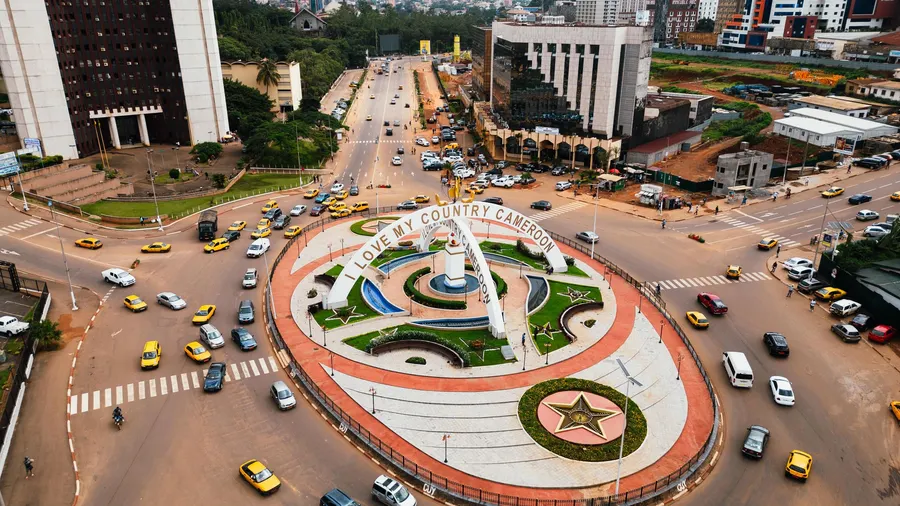 Vista aérea de una rotonda concurrida en Yaundé, Camerún, con tráfico y paisaje urbano