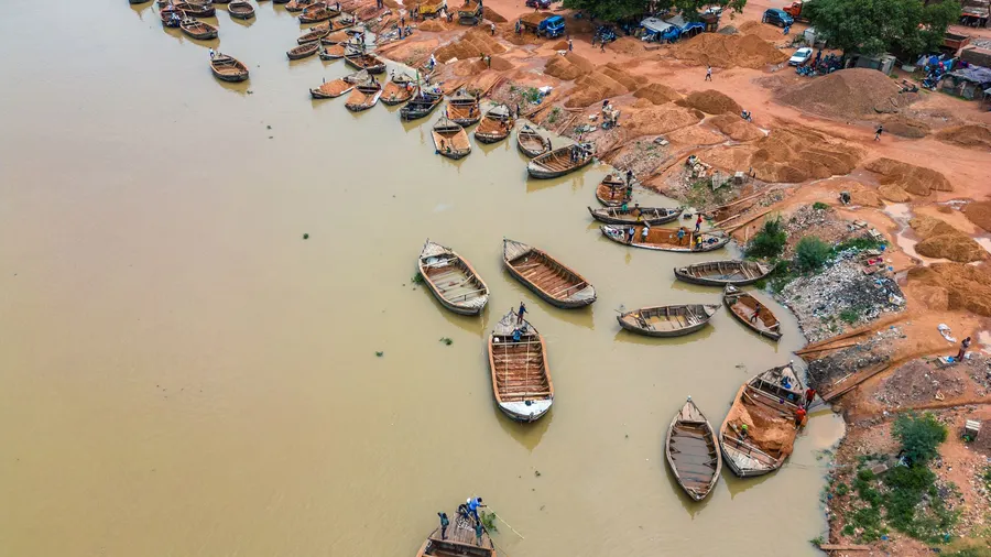 Vista aérea de embarcaciones de madera a lo largo del río Níger en Bamako, Malí, con intensa actividad en la orilla