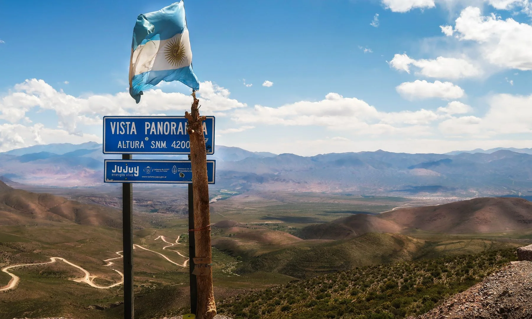 Scenic vista in Jujuy, Argentina with vibrant mountains and waving flag under a clear sky.
