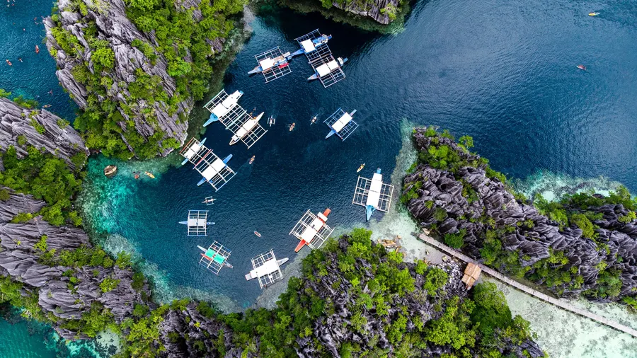 Botes en una laguna turquesa rodeada de formaciones rocosas en El Nido, Palawan, Filipinas