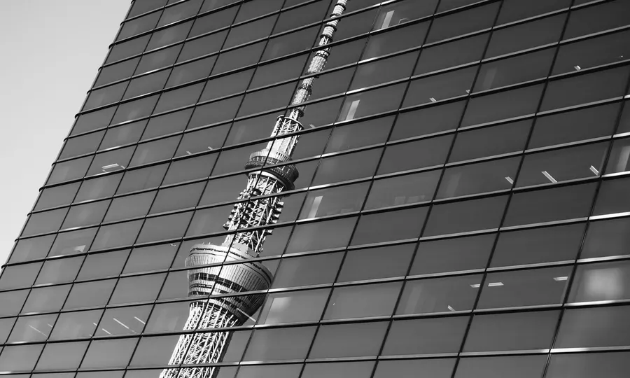 Reflejo de Tokyo Skytree en la fachada de vidrio de un edificio moderno en Tokio, en blanco y negro