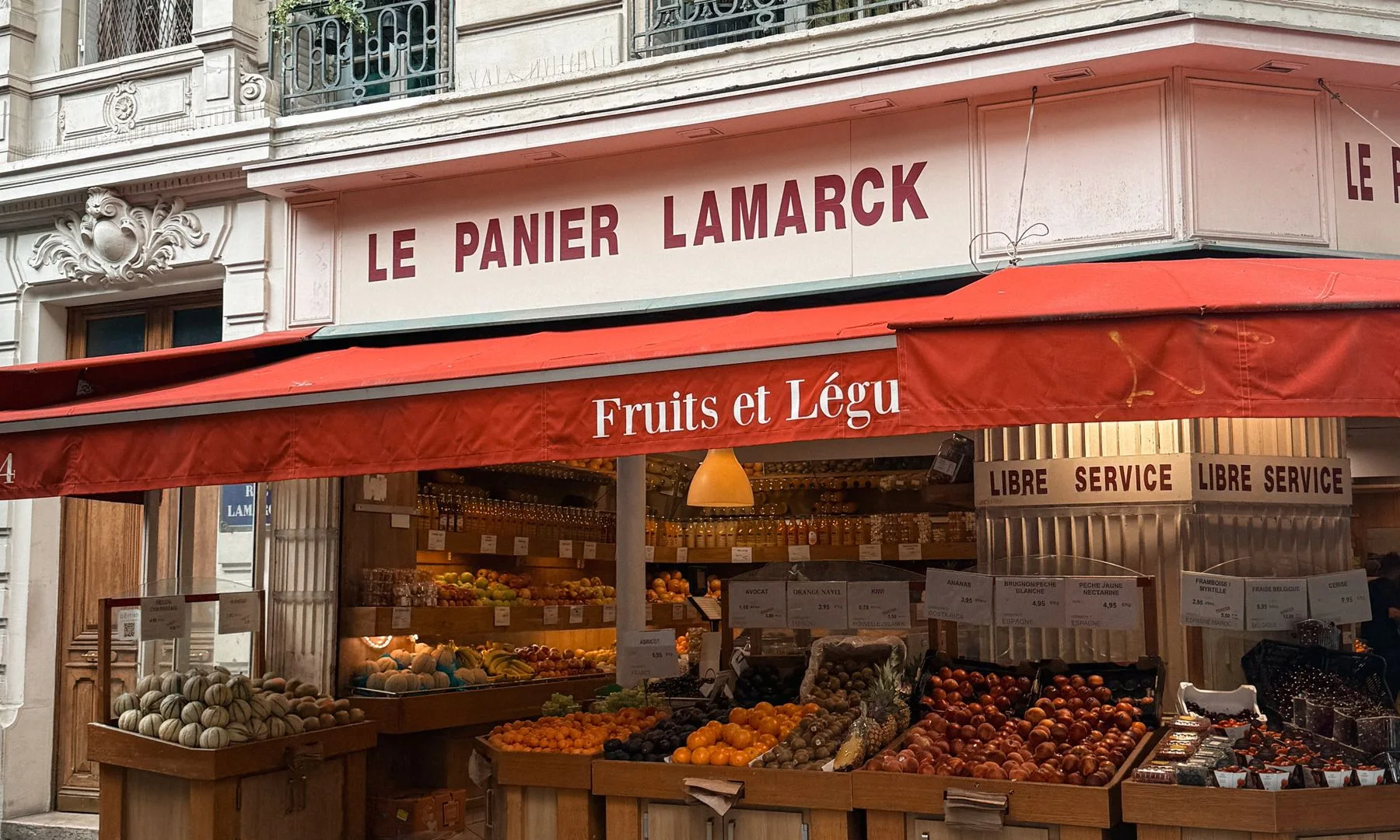 Explore a traditional Parisian street market offering fresh fruits and vegetables in a classic architectural setting.
